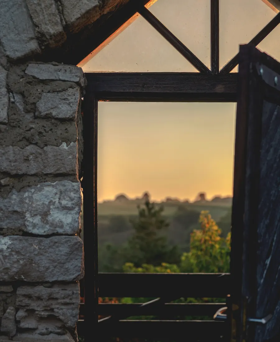 An open wooden door looking out over hills at sunset